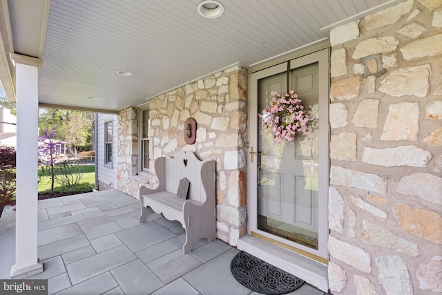 property entrance featuring covered porch and stone siding