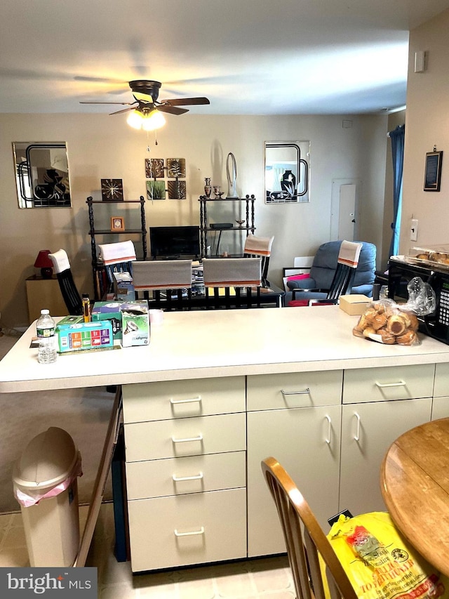 interior space featuring light countertops, a ceiling fan, open floor plan, and light tile patterned floors