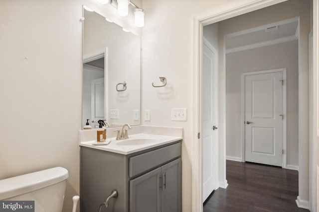 bathroom with vanity, ornamental molding, toilet, and wood finished floors