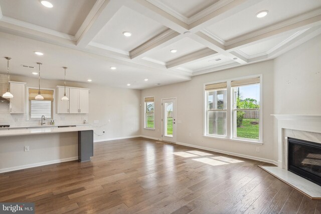 unfurnished living room with beamed ceiling, a wealth of natural light, and dark wood-type flooring