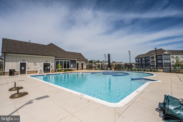 community pool with a patio and fence