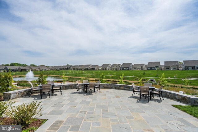 view of patio with a residential view, outdoor dining space, and a water view