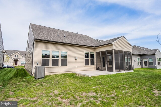back of property featuring roof with shingles, a sunroom, central AC unit, a patio area, and a yard