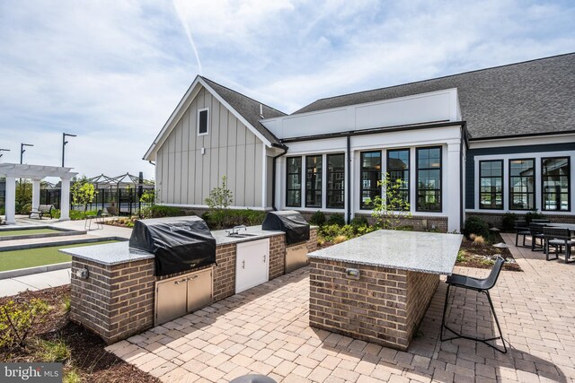 view of patio with area for grilling, an outdoor kitchen, and a pergola