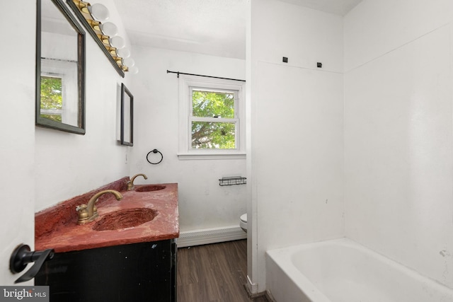 bathroom featuring double vanity, wood finished floors, a sink, baseboards, and toilet