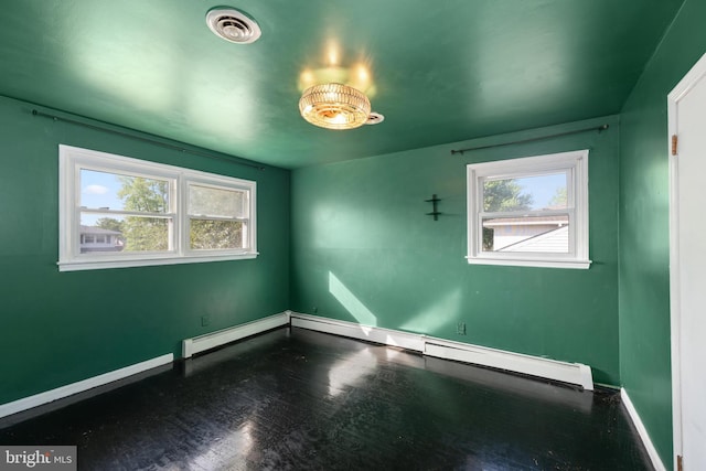 unfurnished room with baseboards, baseboard heating, wood finished floors, and visible vents
