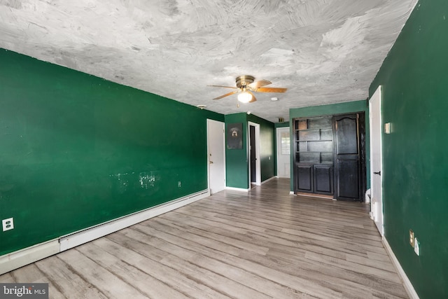 unfurnished living room with baseboards, a baseboard radiator, a ceiling fan, and wood finished floors