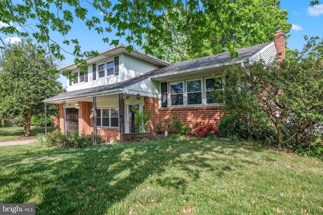 tri-level home with a chimney, a front yard, and brick siding
