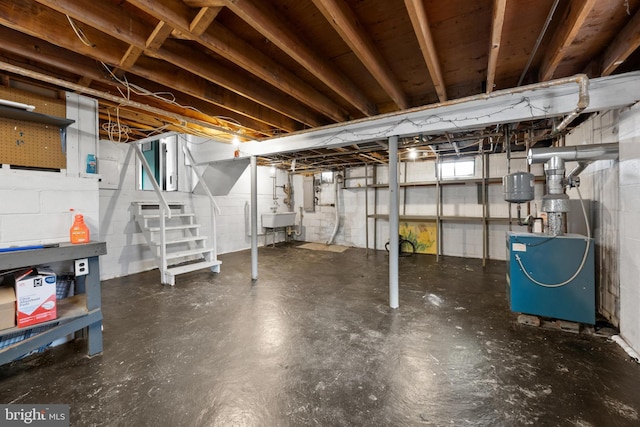 unfinished below grade area with a sink, stairs, and a heating unit