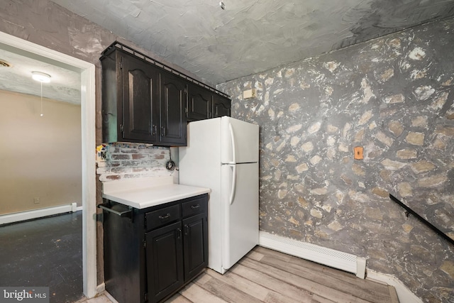 kitchen featuring light countertops, baseboards, a baseboard radiator, freestanding refrigerator, and light wood-style floors