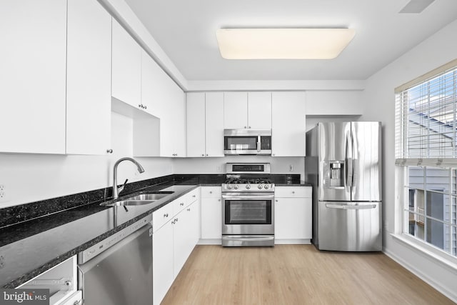 kitchen with stainless steel appliances, a sink, light wood-type flooring, and white cabinets
