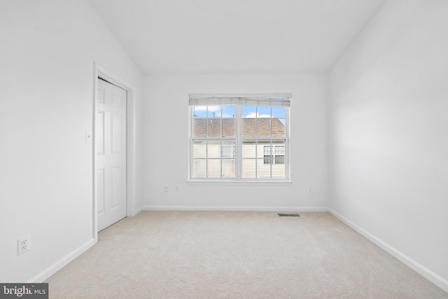 carpeted spare room featuring baseboards and vaulted ceiling