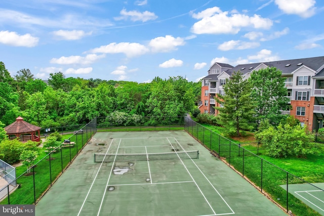 view of tennis court featuring fence and a gazebo