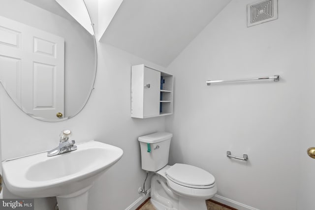 half bathroom with baseboards, lofted ceiling, toilet, and a sink