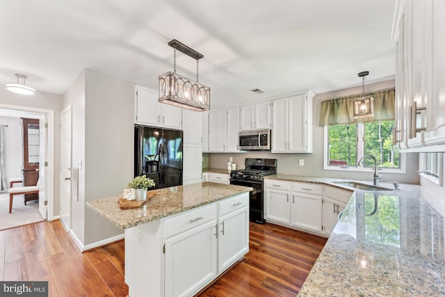13213 Windy Leaf Ct, Woodbridge, VA 22192 - kitchen with wood finished floors, light stone countertops, white cabinets, a sink, and black appliances