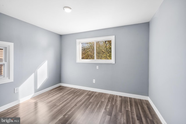 spare room with baseboards and wood finished floors