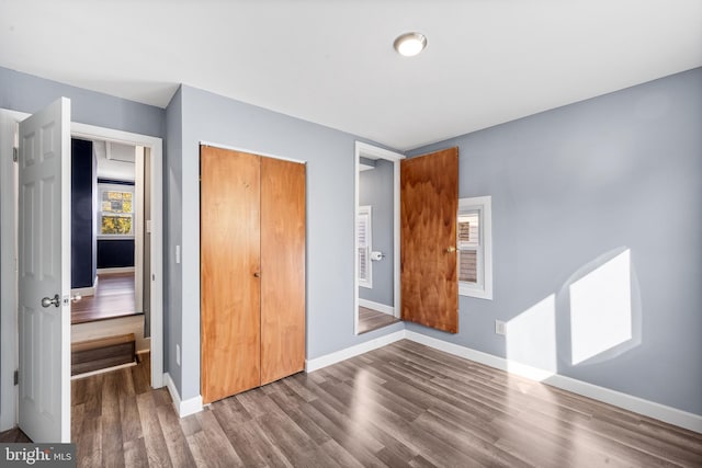 unfurnished bedroom with baseboards, wood finished floors, and a closet