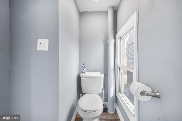 bathroom with baseboards, wood finished floors, and toilet