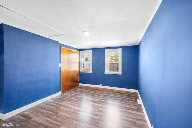 empty room with baseboards, visible vents, wood finished floors, and attic access