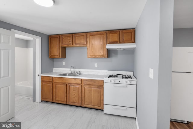 kitchen featuring white appliances, light countertops, under cabinet range hood, brown cabinets, and a sink