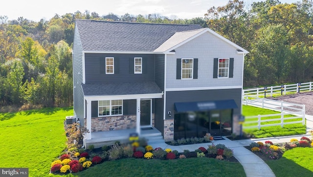 view of front of property with central AC, fence, a shingled roof, and a front lawn