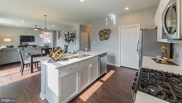 kitchen featuring a sink, light countertops, stainless steel appliances, a ceiling fan, and open floor plan