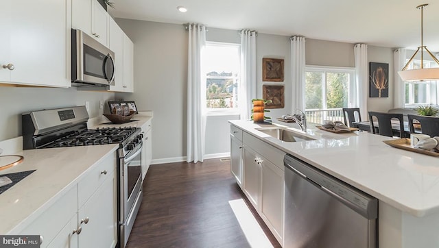 kitchen featuring white cabinets, appliances with stainless steel finishes, a sink, a kitchen island with sink, and dark wood finished floors