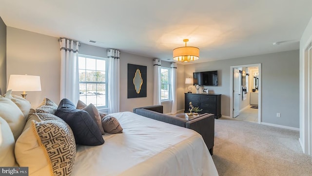 bedroom with baseboards, ensuite bath, and light colored carpet