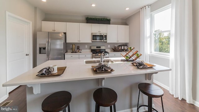 kitchen with light countertops, white cabinetry, a kitchen island with sink, and stainless steel appliances