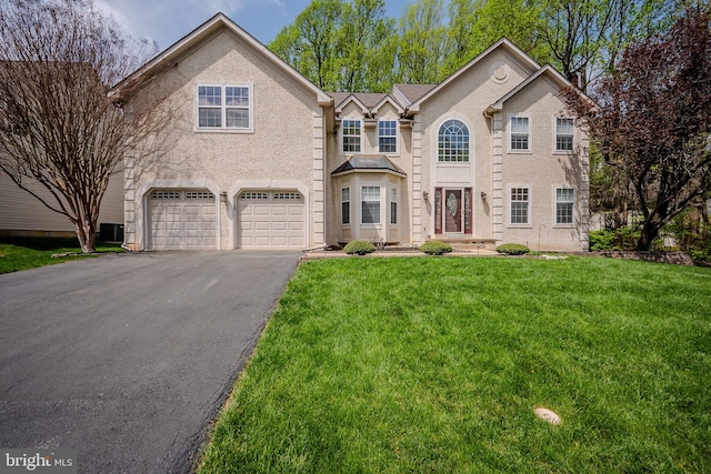 traditional-style home featuring stucco siding, aphalt driveway, a front yard, and a garage