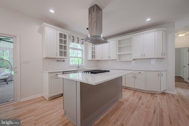 kitchen with open shelves, island range hood, gas cooktop, light wood-type flooring, and a sink