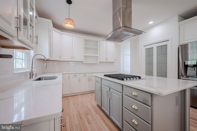 kitchen with gray cabinets, island range hood, appliances with stainless steel finishes, a sink, and white cabinets