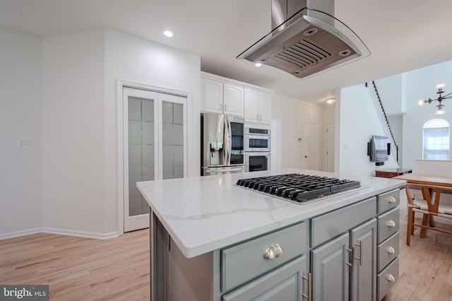 kitchen with light wood-style floors, range hood, gray cabinets, and stainless steel appliances