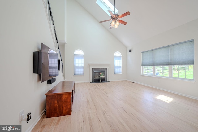 unfurnished living room with high vaulted ceiling, ceiling fan, a wealth of natural light, and wood finished floors
