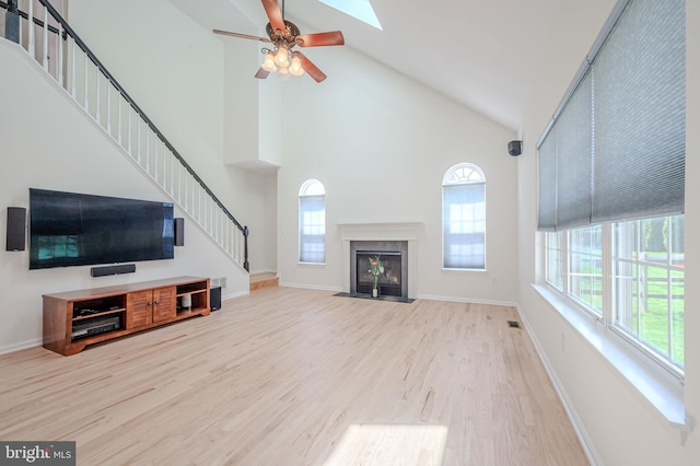 unfurnished living room with wood finished floors, a healthy amount of sunlight, and stairway