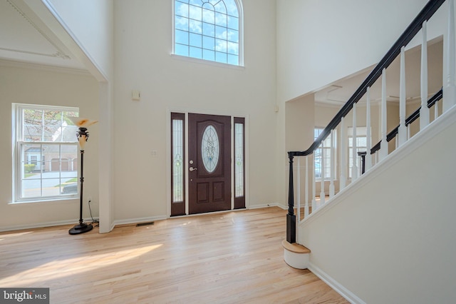 entryway featuring baseboards, a high ceiling, wood finished floors, and stairway