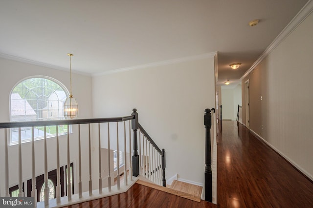 hall with crown molding, an upstairs landing, wood finished floors, baseboards, and a notable chandelier