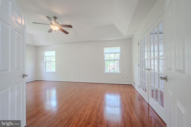 unfurnished room featuring a ceiling fan, a tray ceiling, french doors, and wood finished floors