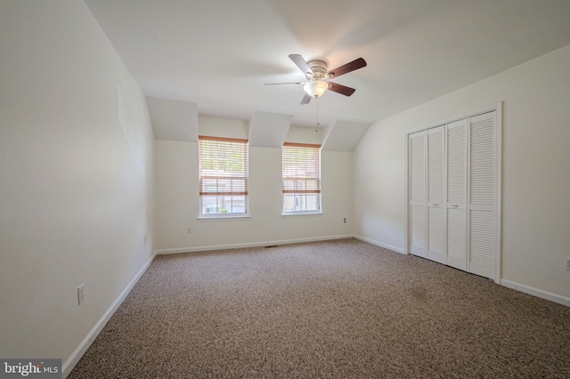 unfurnished bedroom with carpet floors, a ceiling fan, baseboards, vaulted ceiling, and a closet