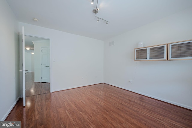 unfurnished room with baseboards, wood finished floors, and visible vents