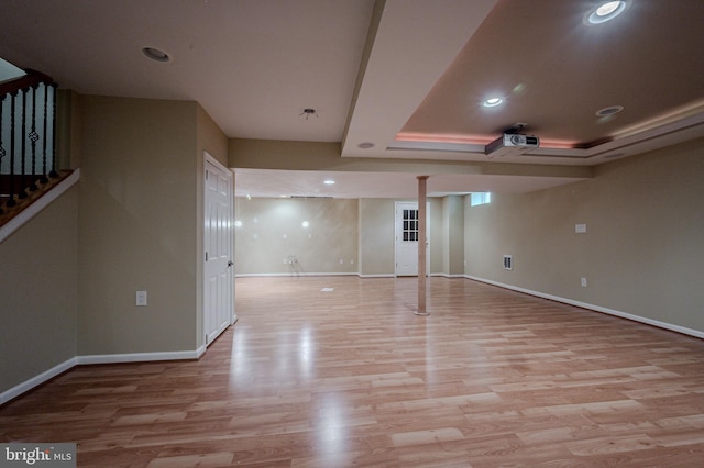 spare room with recessed lighting, baseboards, light wood finished floors, and a raised ceiling