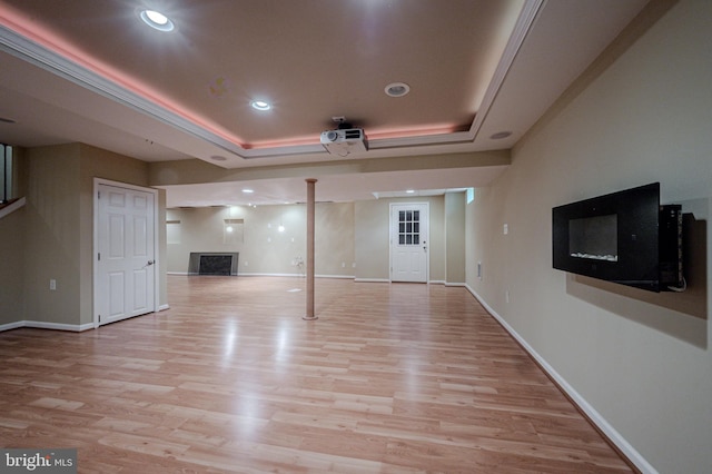 unfurnished living room with light wood-type flooring, a raised ceiling, and a fireplace