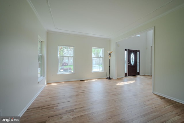 unfurnished living room with baseboards, ornamental molding, and light wood finished floors