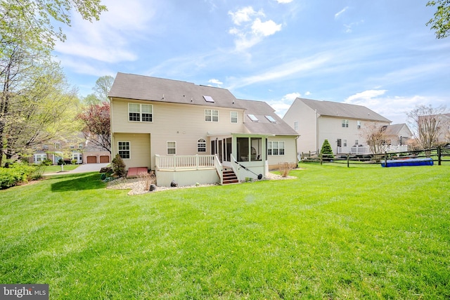 back of house featuring a yard, fence, a wooden deck, and a sunroom