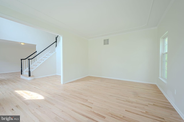 unfurnished living room featuring baseboards, ornamental molding, wood finished floors, and stairway