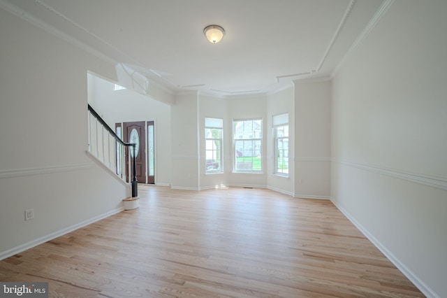 unfurnished living room featuring baseboards, ornamental molding, light wood-style flooring, and stairway