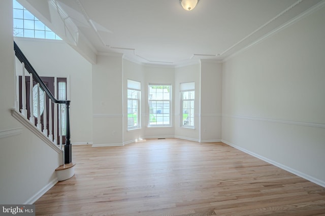 unfurnished living room with ornamental molding, wood finished floors, and a wealth of natural light