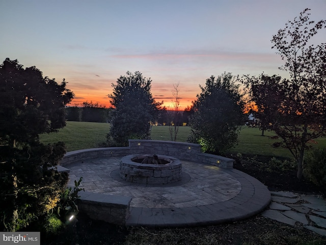 patio terrace at dusk featuring a lawn and an outdoor fire pit