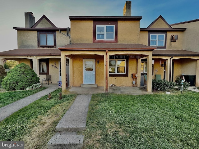 multi unit property featuring a chimney, a front yard, and stucco siding