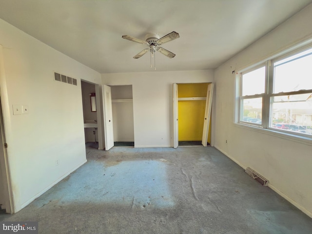 unfurnished bedroom featuring carpet floors, baseboards, visible vents, and two closets